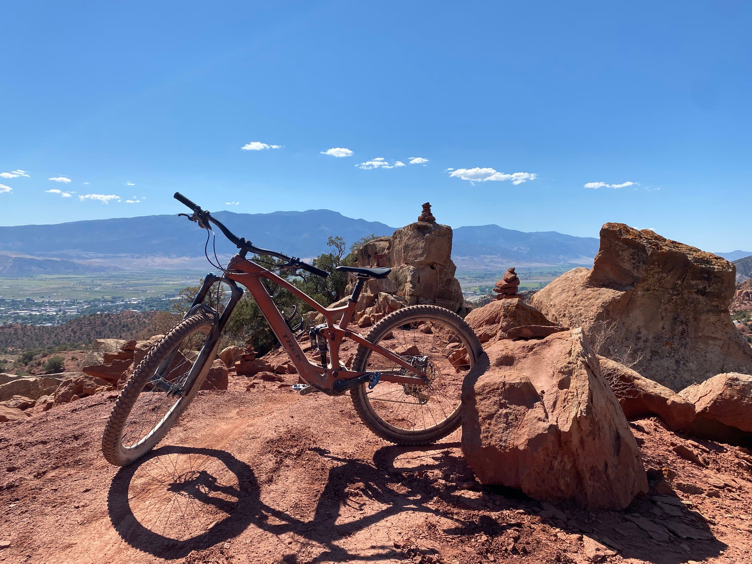 Mountain bike resting against red rock boulders under a blue Utah sky