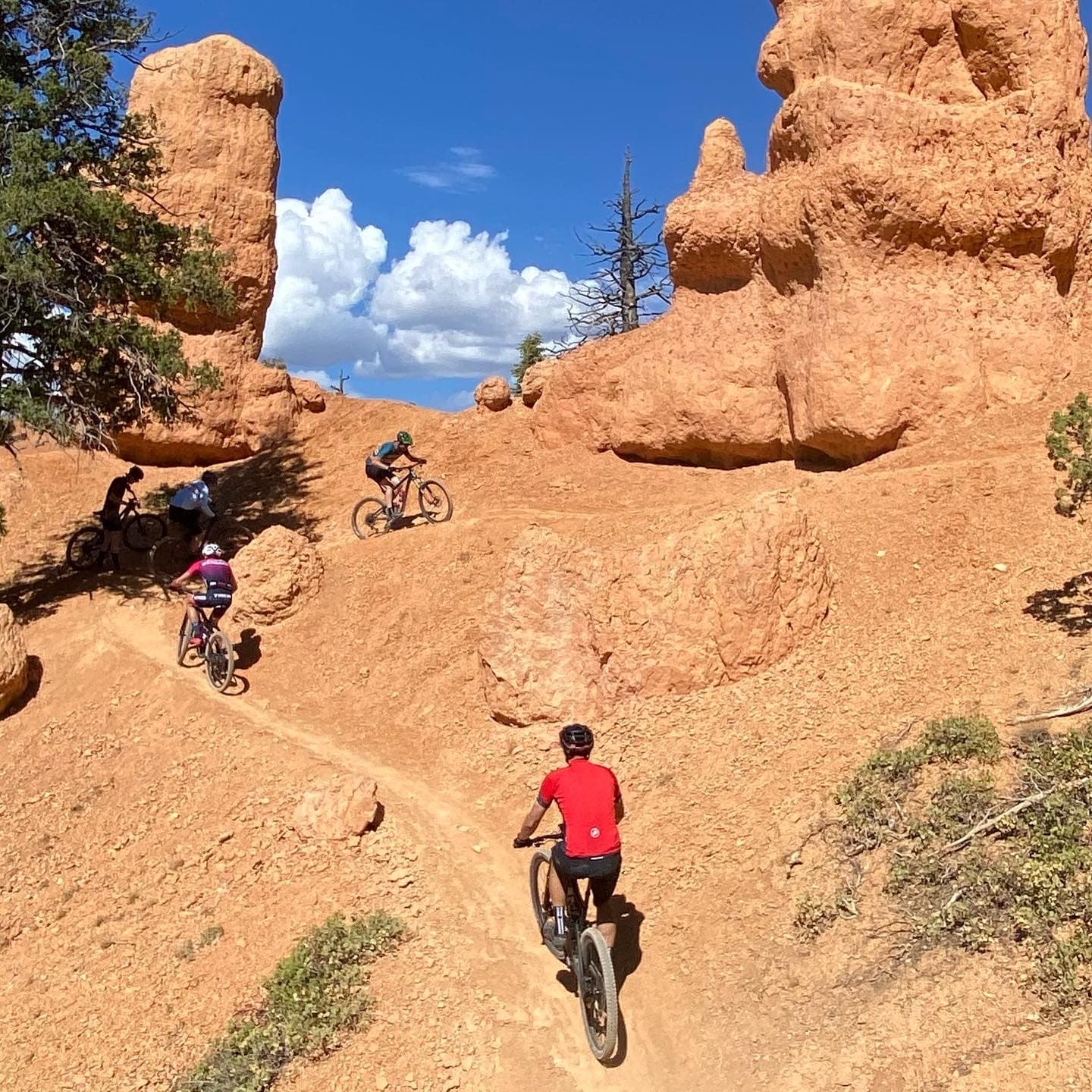 Group of riders climbing between red rock hoodoos
